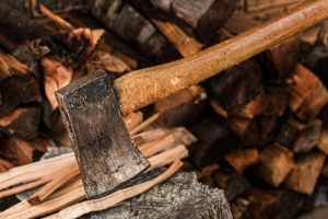 axe on stump of tree and firewood in the background