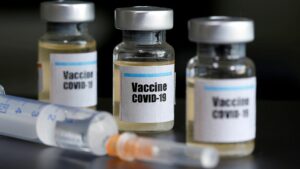 Covid vaccine bottles and filled hypodermic needle