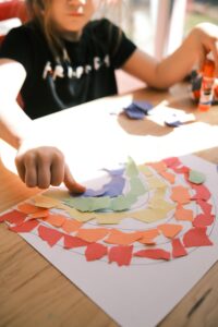 girl creating rainbow with colored paper