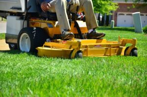 person mowing lawn on yellow mower